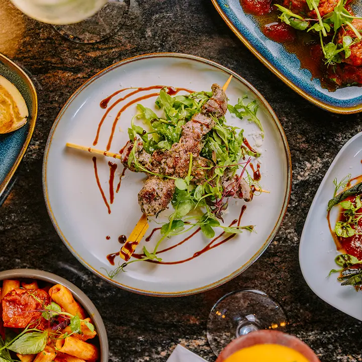 cicchetti-lounge-york-italian-small-plates-cocktails Overhead view of grilled skewers with salad, Italian small plates, pasta and cocktails at Cicchetti Lounge in York.