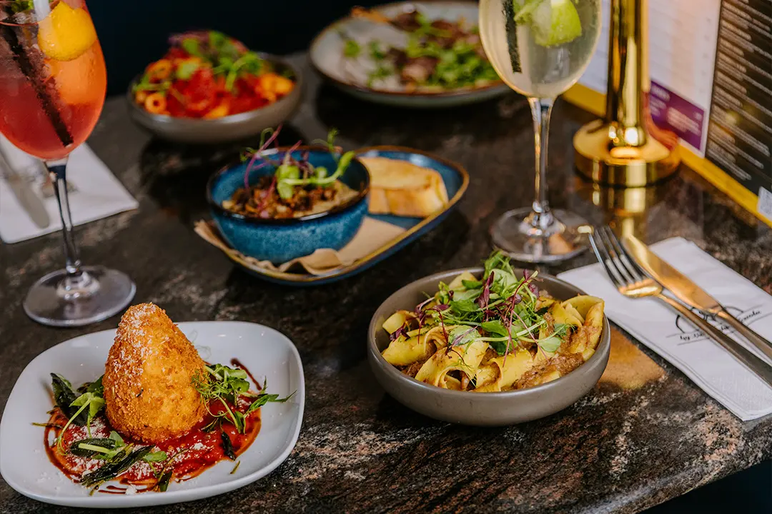 cicchetti-lounge-york-tapas-pasta-cocktails Italian small plates and ribbon pasta with two cocktails on a marble dining table at Cicchetti Lounge in York.